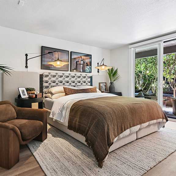 A bedroom with a large bed and a chair.
