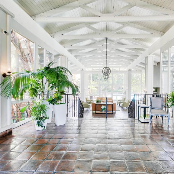 a large room with tables and plants in it  at Mediterranean Village Costa Mesa, Costa Mesa, California