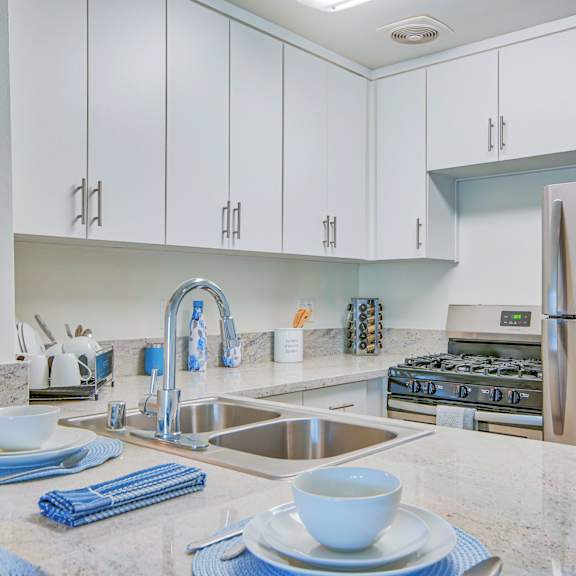 A kitchen with a stainless steel refrigerator and a granite countertop.