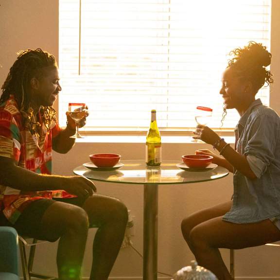 Two people sitting at a table with food and drinks.