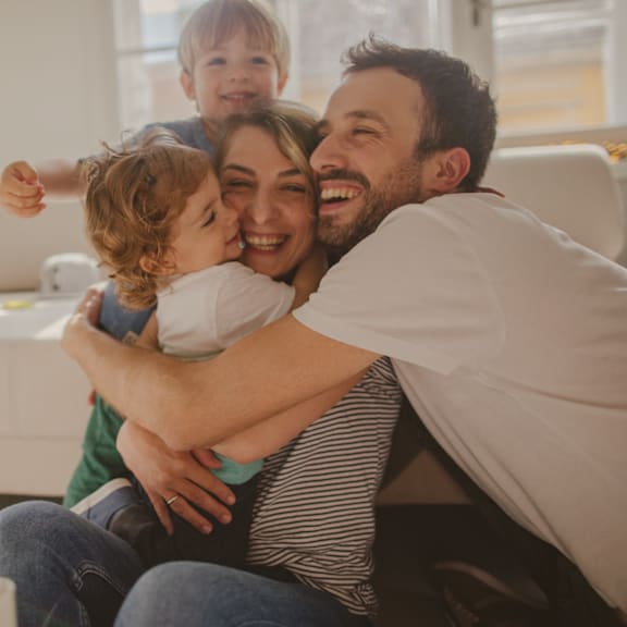 A family of three is sitting closely together on a couch.