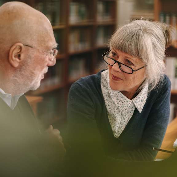 an older man and woman sitting at a table in a library at The Carillon, Greensboro, NC
