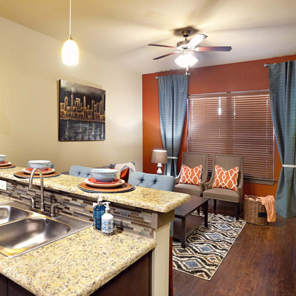 a kitchen and living room with a granite counter top at Urban Square, Denton, 76210