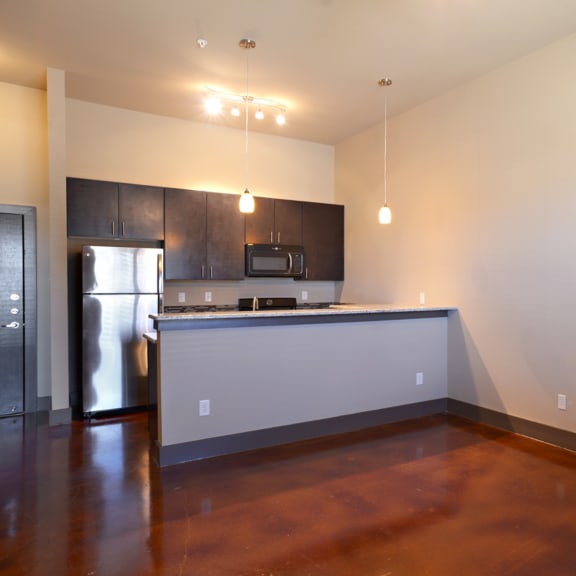 an empty living room with a kitchen and a hard wood floor at Urban Square, Denton, 76210