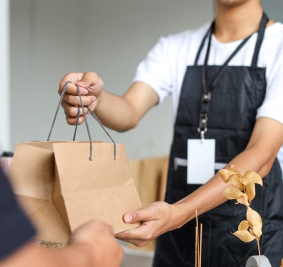 a person handing a paper bag to another person at The BLVD at Wilson Crossings in Wyoming, MI 49418