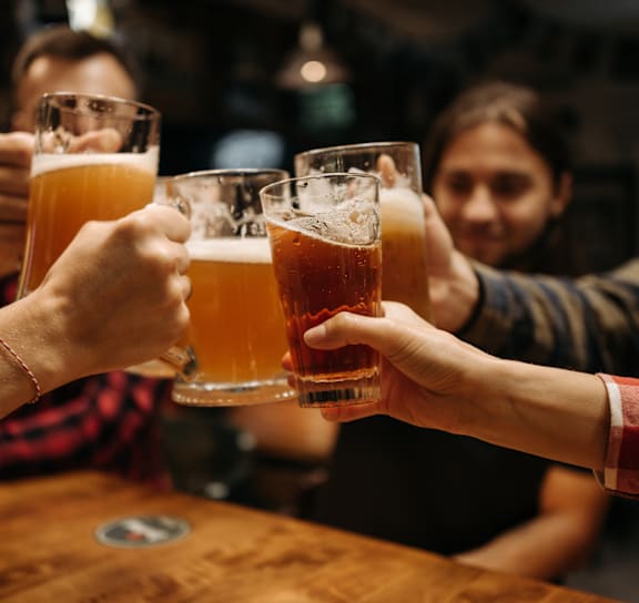 Group of people toasting with beer glasses in a bar at The Yancey Apartments, Charlotte, NC