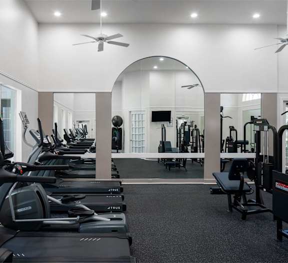 A gym with a variety of equipment including treadmills, weights, and exercise machines.