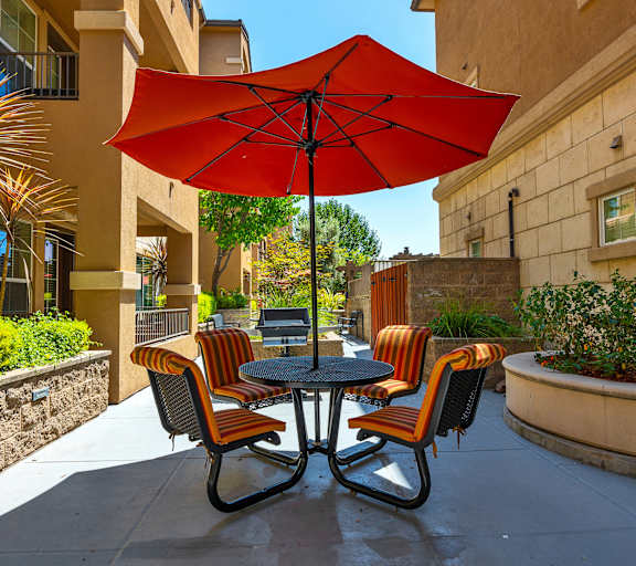 a patio with a table and chairs under a red umbrella