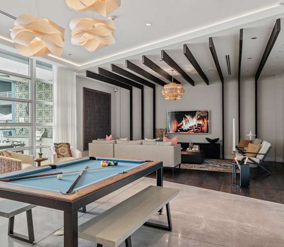 A pool table is in the middle of a room with a bench and a chair.