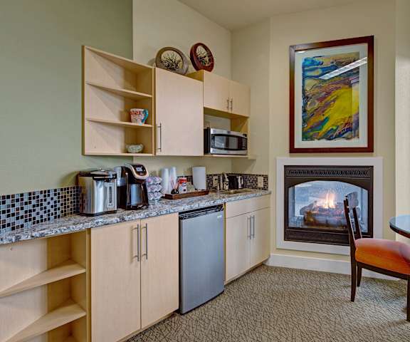 A kitchen with a fireplace and a dining room with a table and chairs at Alpine Apartments. 