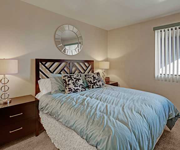 A bedroom with a bed and a window with vertical blinds at Alpine Apartments. 