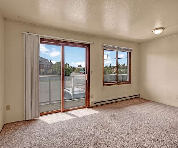 An empty living room with sliding glass doors to a balcony at Arbor Pointe Apartments
