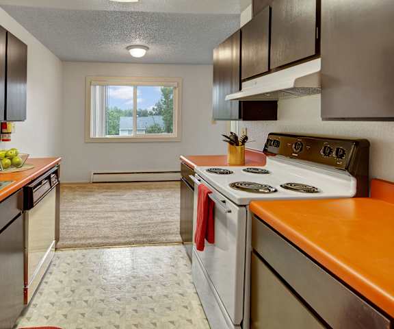 A kitchen with an orange counter top and white appliances at Arctic Sun Apartments. 