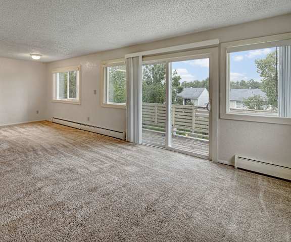 An empty living room with sliding glass doors to a balcony at Arctic Sun Apartments. 