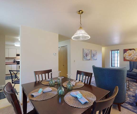 A dining room and living room with a wooden table, chairs, and a couch at Birchwood Homes Apartments. 
