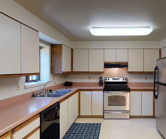 A kitchen with white cabinets and stainless steel appliances at Birchwood Homes Apartments. 