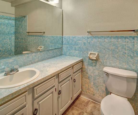 A bathroom at Castle Apartments with blue and white marbled tile walls and blue and white marbled counters at Castle Apartments.  
