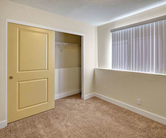 An empty bedroom with a window and closet at City View Apartments. 