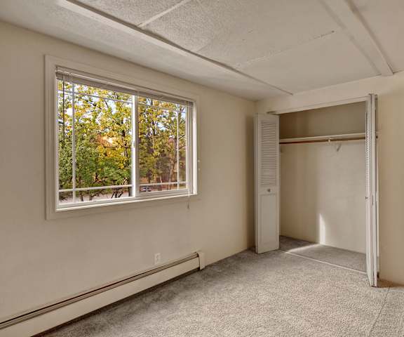 An empty bedroom with a window and a closet at College View Apartments. 