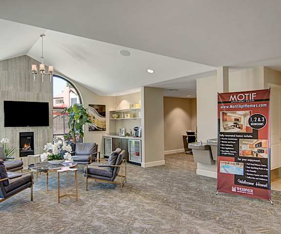 The resident lounge with a fireplace, couches, decorations, plush chairs, and coffee tables at Motif Apartments. 