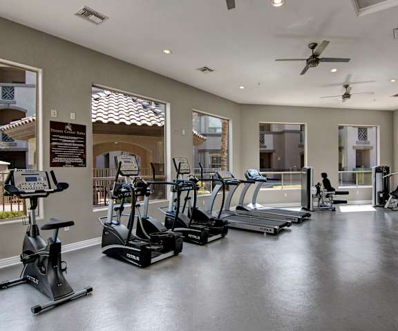 A spacious gym with cardio machines, windows, ceiling fans, TVs, and weights at Sonoma Landing Apartment Homes. 