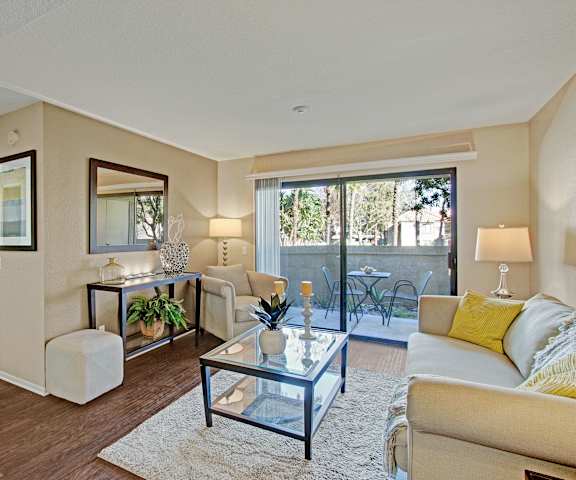 A living room with a couch, glass coffee table, and door to the patio at Castlepark Apartments. 