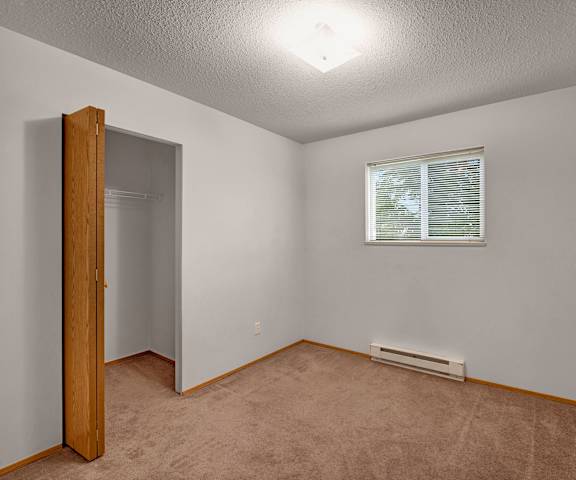 An empty bedroom with a window and a closet at Carrington Place. 