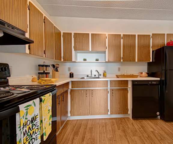 A kitchen with black appliances and wooden cabinets at Centre Pointe Plaza.