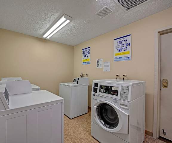 The laundry room with shelves, washers, and dryers at Stirling Place Apartment Homes. 
