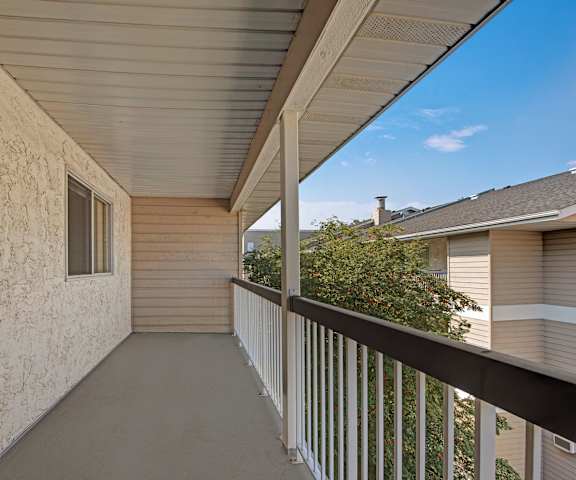 A concrete and metal balcony with a gorgeous view of at the other apartments and trees at Stirling Place Apartment Homes. 