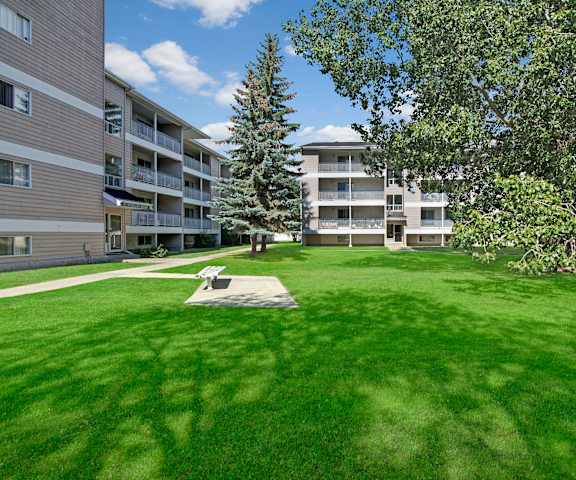 The large, grassy area with a pathway and trees behind the apartment buildings at Stirling Place Apartment Homes. 
