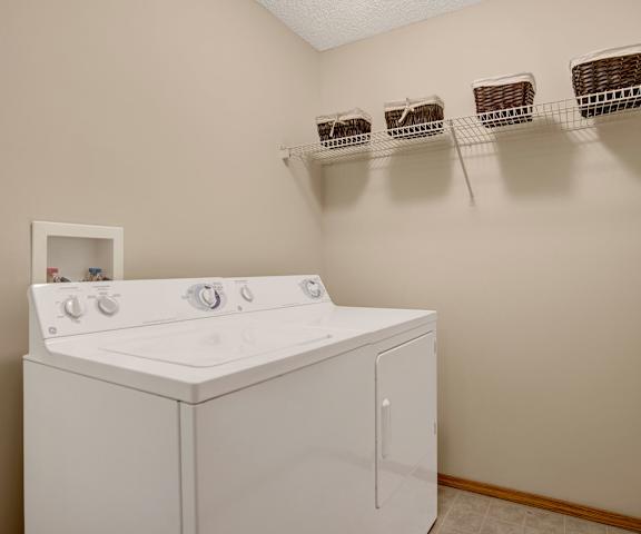 The laundry room with shelves, a washer, and a dryer at Wellington Manor Apartment Homes. 