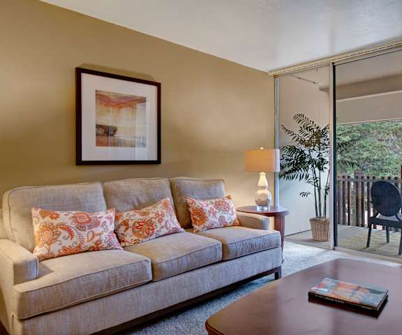 The living room with a couch, coffee table, decorations, a TV, and balcony at Copper Stone Apartments. 