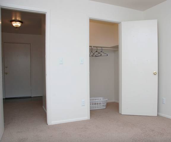 An empty carpeted bedroom with a closet at Hyde Park North Apartments. 