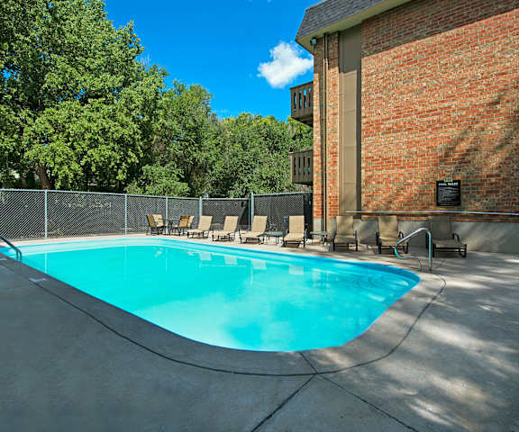 Hyde Park Outdoor Swimming Pool The turquoise outdoor pool with pool chairs, tables, and chairs with the apartments in the background at Hyde Park.