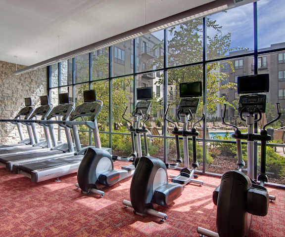 A spacious gym with cardio machines, windows, TVs, and weights at Residence at the COR Apartment Homes. 