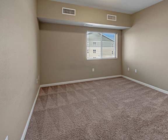 An empty bedroom with a window at Dakota Commons Apartments. 