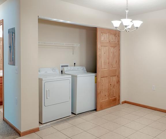 Full-Size Washer and Dryer with Storage in Every Apartment Home The laundry room with shelves, a washer, and a dryer at Rockridge Apartment Homes.