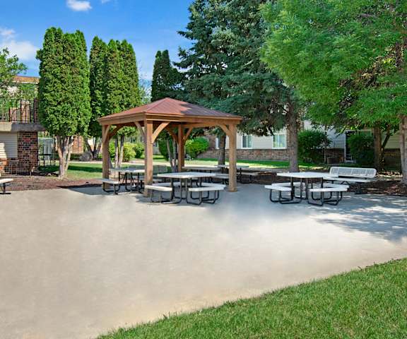 Windscape Gazebo A part of the courtyard with a patio, benches, and a gazebo surrounded by grassy and trees with the apartment buildings in the background at Windscape Apartment Homes.