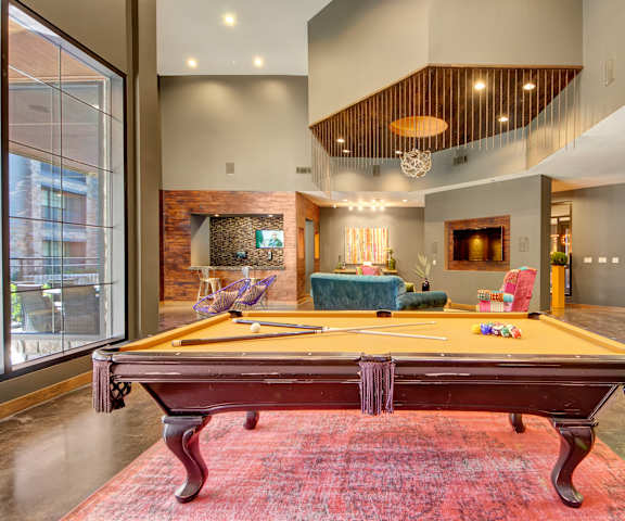 A wonderful resident lounge with tables, chairs, and a pool table at the Enclave at Brookside Apartment Homes. 