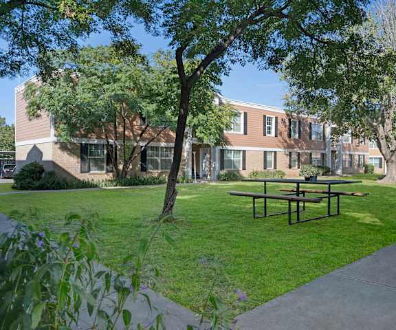 Golden Crest Exterior The courtyard with benches, grass, trees, and shrubs in front of the buildings at Golden Crest.