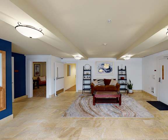 The front lobby with a red couch, coffee table, bookshelves, and decorations at Forest Hills Estates.