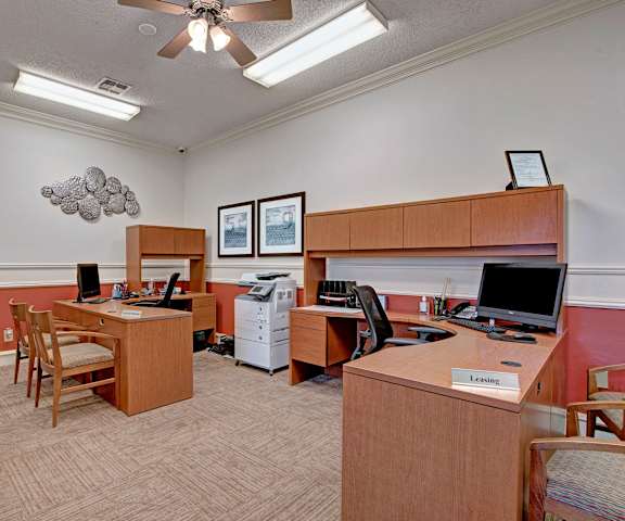 The leasing office with two brown desks, chairs, desktop computers, a printer, and a copier at St. James Place Apartment Homes. 