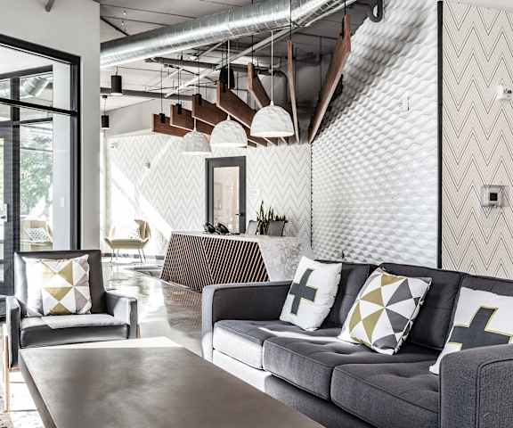 The amazing resident lounge with couches, decorations, large windows, unique overhead lighting, plush chairs, and coffee tables at Vim +Vigor Lofts. 