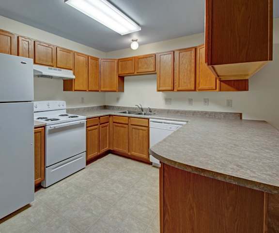 Unit Kitchen at Dakota Apartments A kitchen with white appliances and counters at Dakota Apartments.