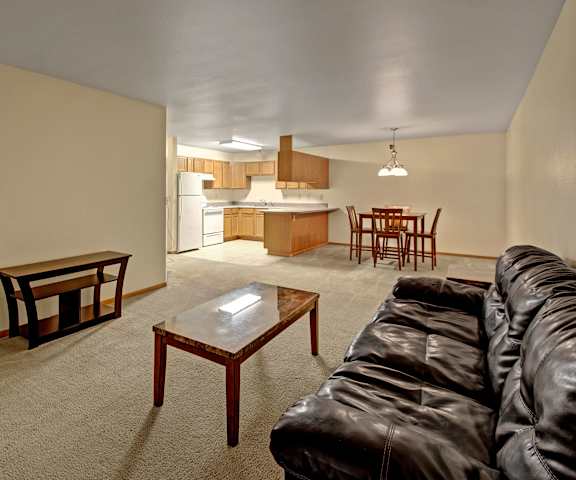 The living room with a couch, coffee table, and a view of the dining room and kitchen at Dakota Apartments. 