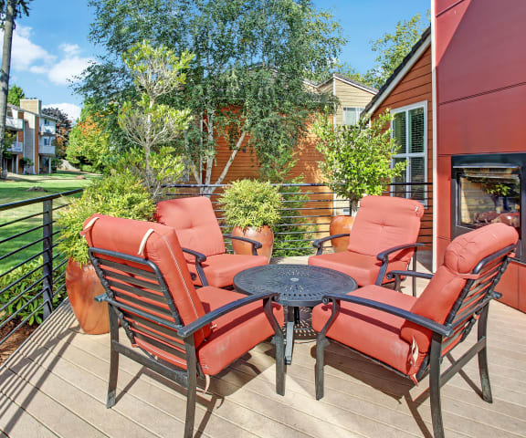 An outdoor porch with a table and chairs with a fireplace for resident use A'Cappella Exterior Apartments in Lynnwood, WA