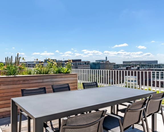 a dining table and chairs on a roof terrace with a view of the city