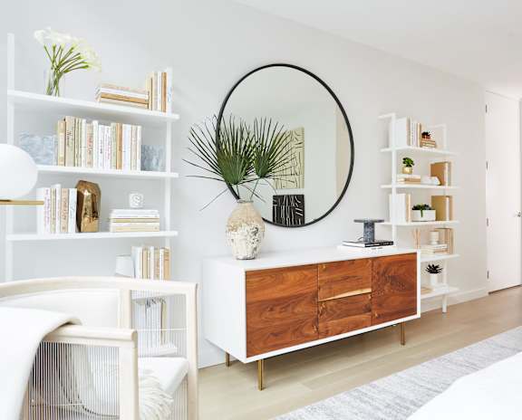 a living room with a dresser and a mirror and shelves