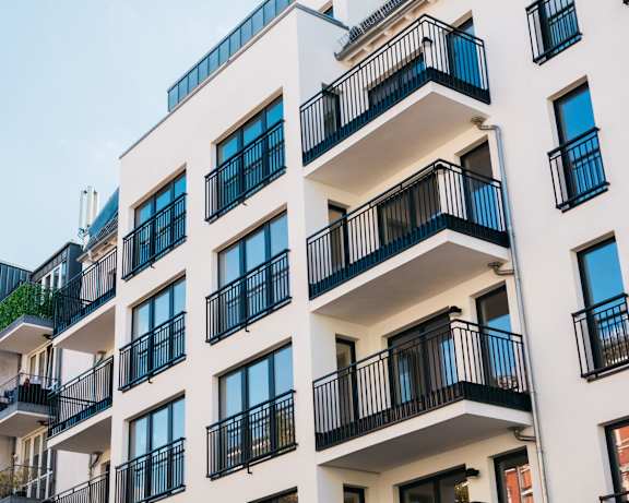 A white apartment building with black railings and balconies.